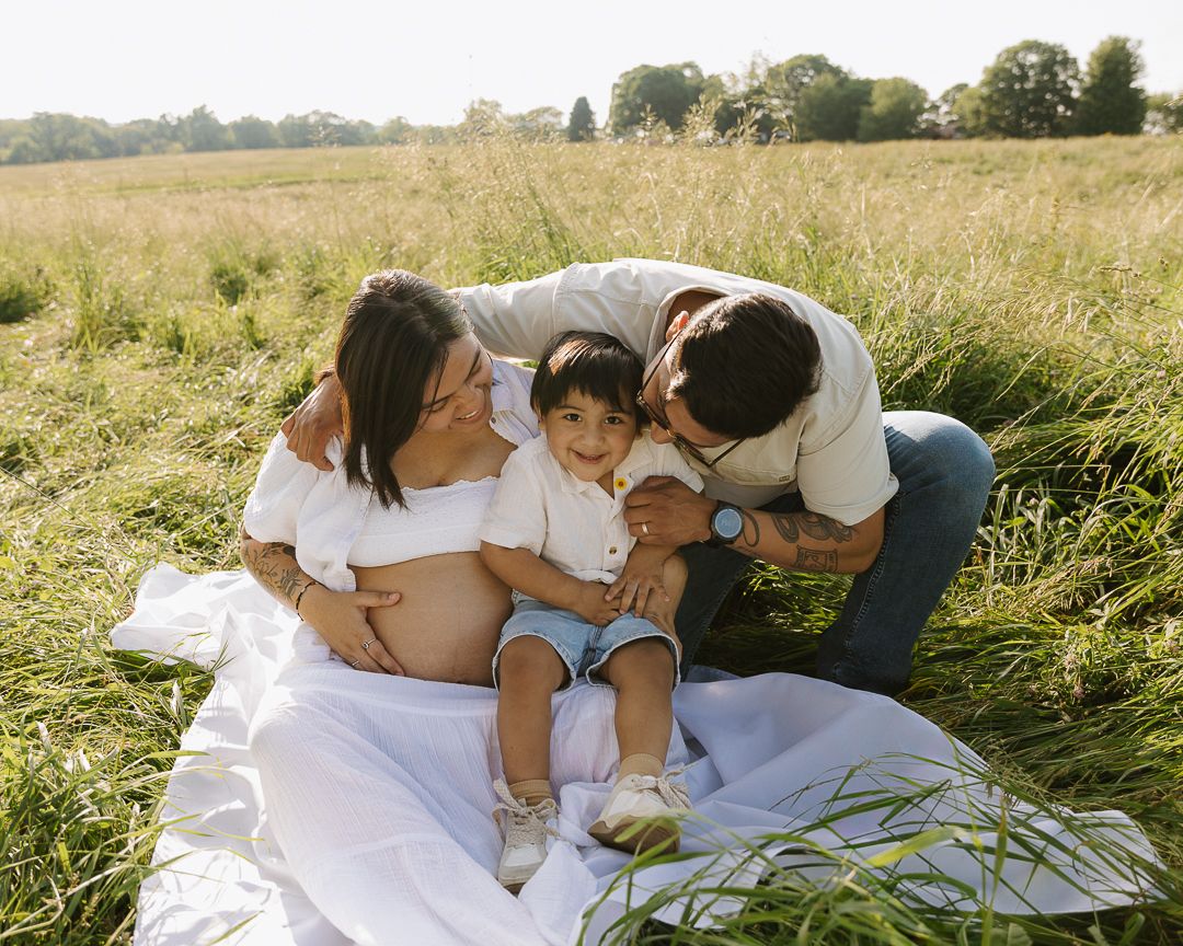 Romantic couple shares tender moments together while relaxing on white blanket in sunny summer meadow.