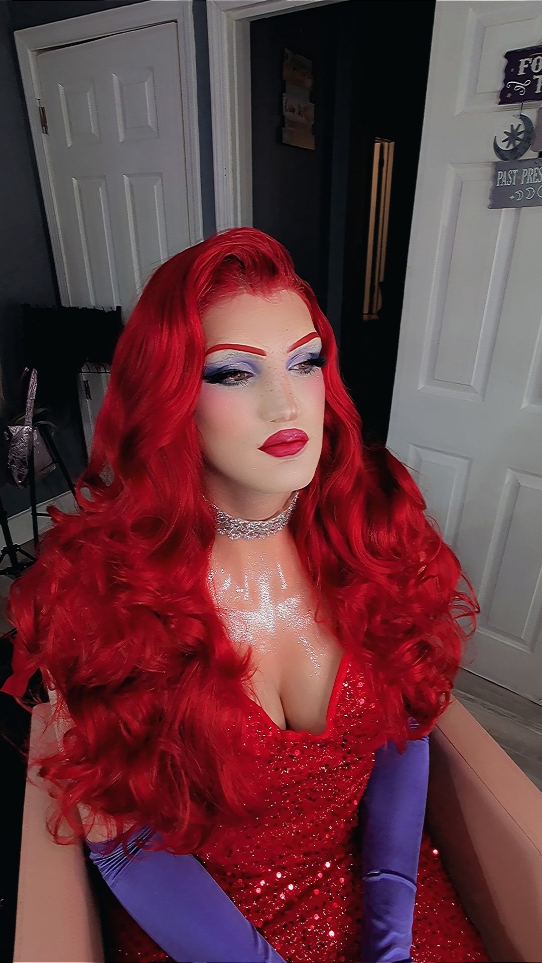Woman in Jessica Rabbit costume with red wig, red sequin dress, purple gloves, dramatic makeup, and silver choker necklace.