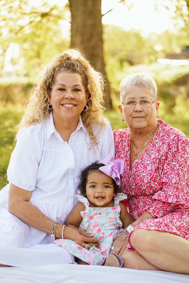 A series of sweet outdoor family portraits showing three generations bonding together in white and pink attire.