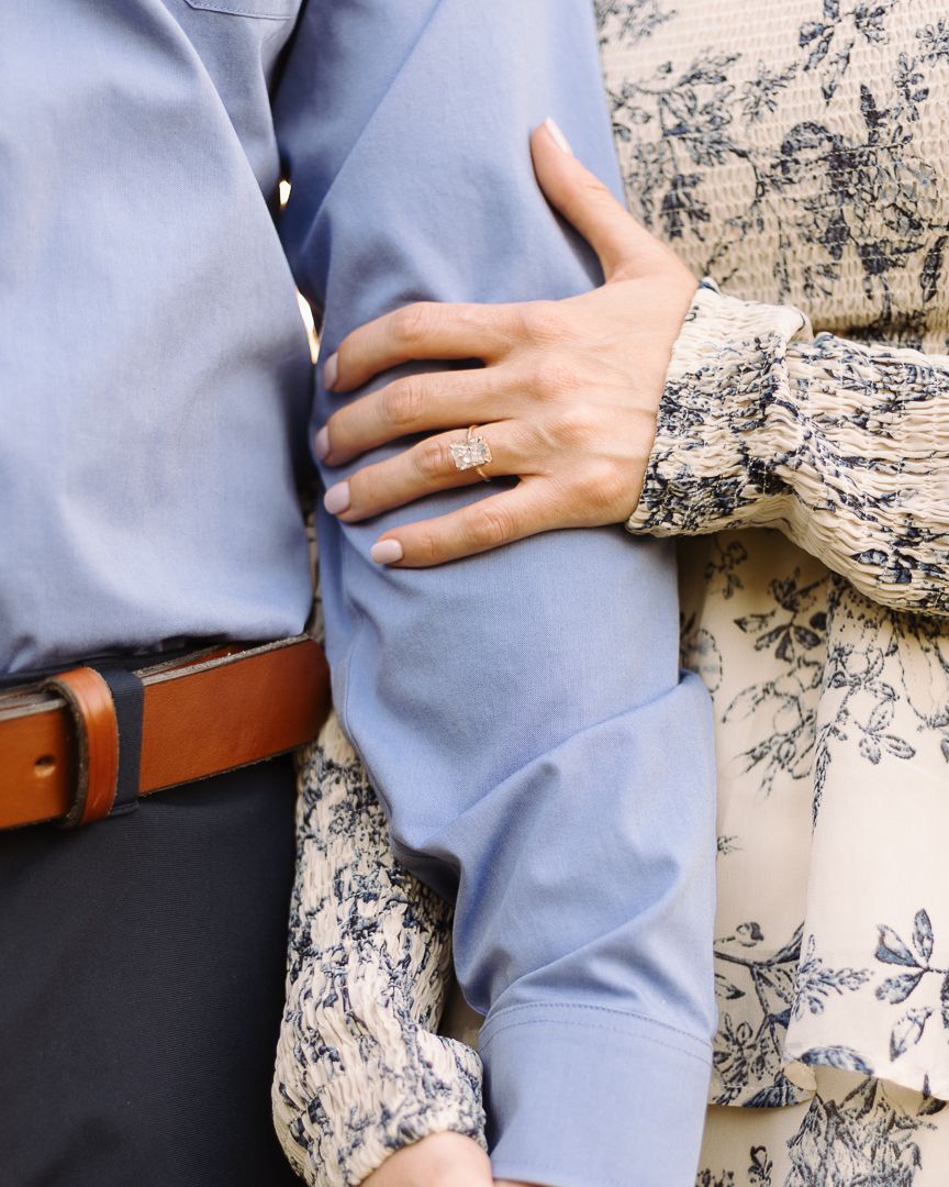 Close-up of couple embracing in blue shirt and floral pattern against textured wall background.