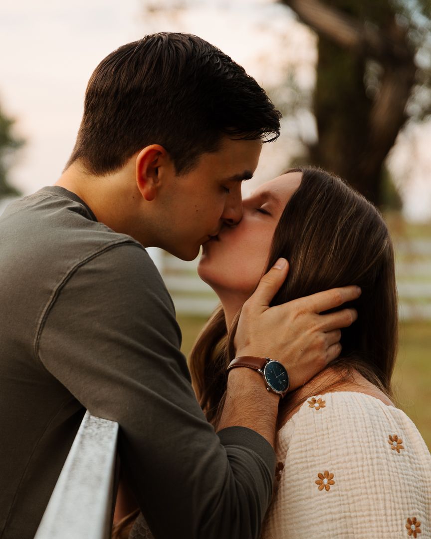 Romantic couple embracing in tender moment outdoors during golden hour.