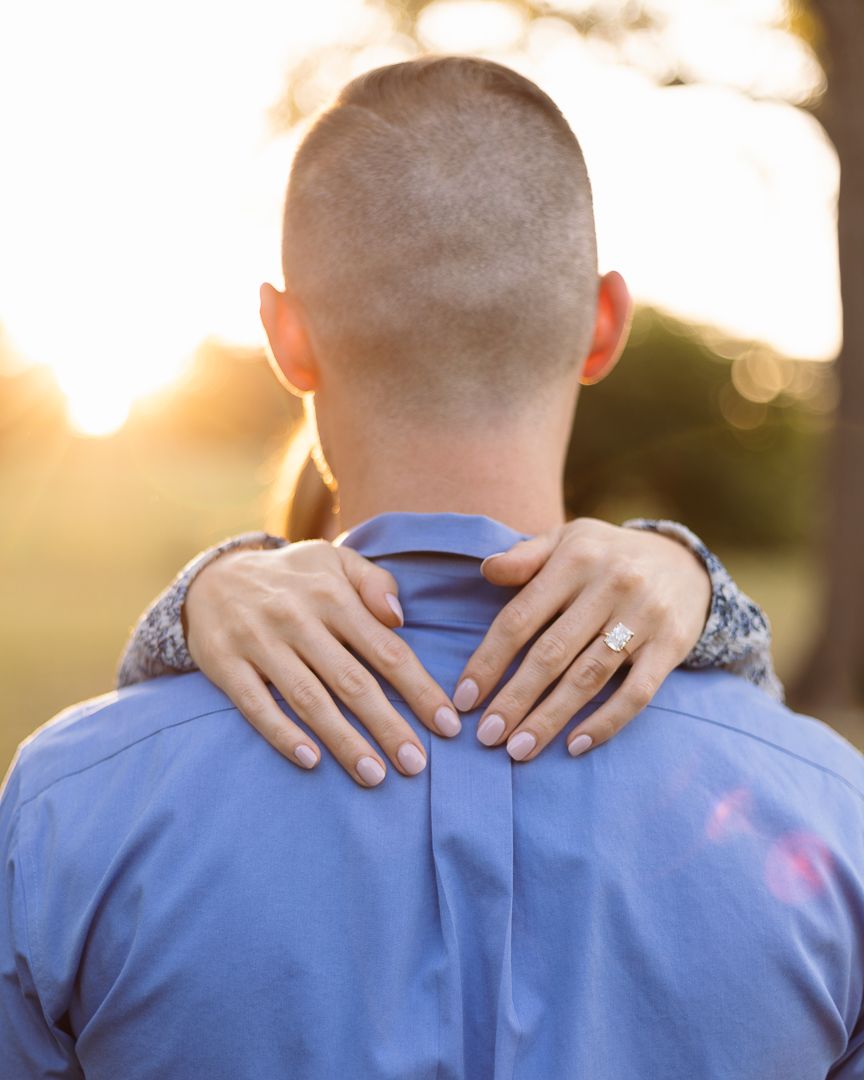 Hands resting on shoulders from behind during a warm sunset golden hour photoshoot.