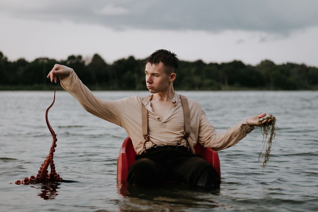 Dramatic water photography series showing red fabric and mysterious poses in lake setting.