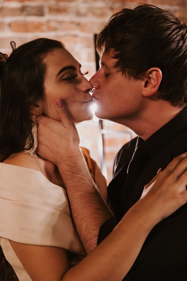 A romantic sequence of intimate kisses between a couple against a brick wall backdrop.