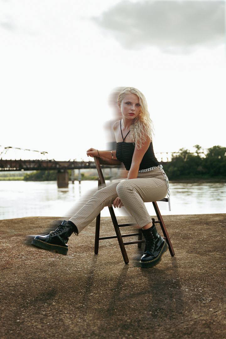 Artistic fashion photos showing a model posing with a vintage wooden chair against an industrial waterfront setting.