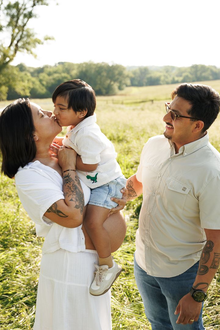 A couple embraces in a sunny field during a romantic afternoon photoshoot.