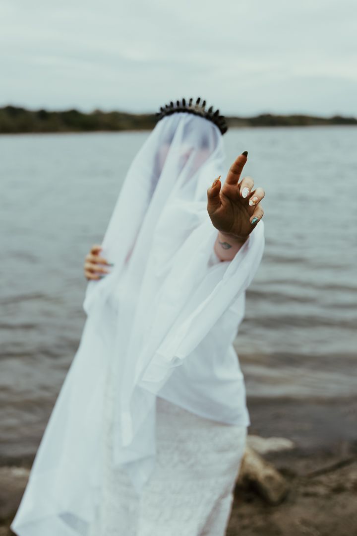 Ethereal white fabric flowing in the wind against a waterfront backdrop creates an abstract artistic composition.