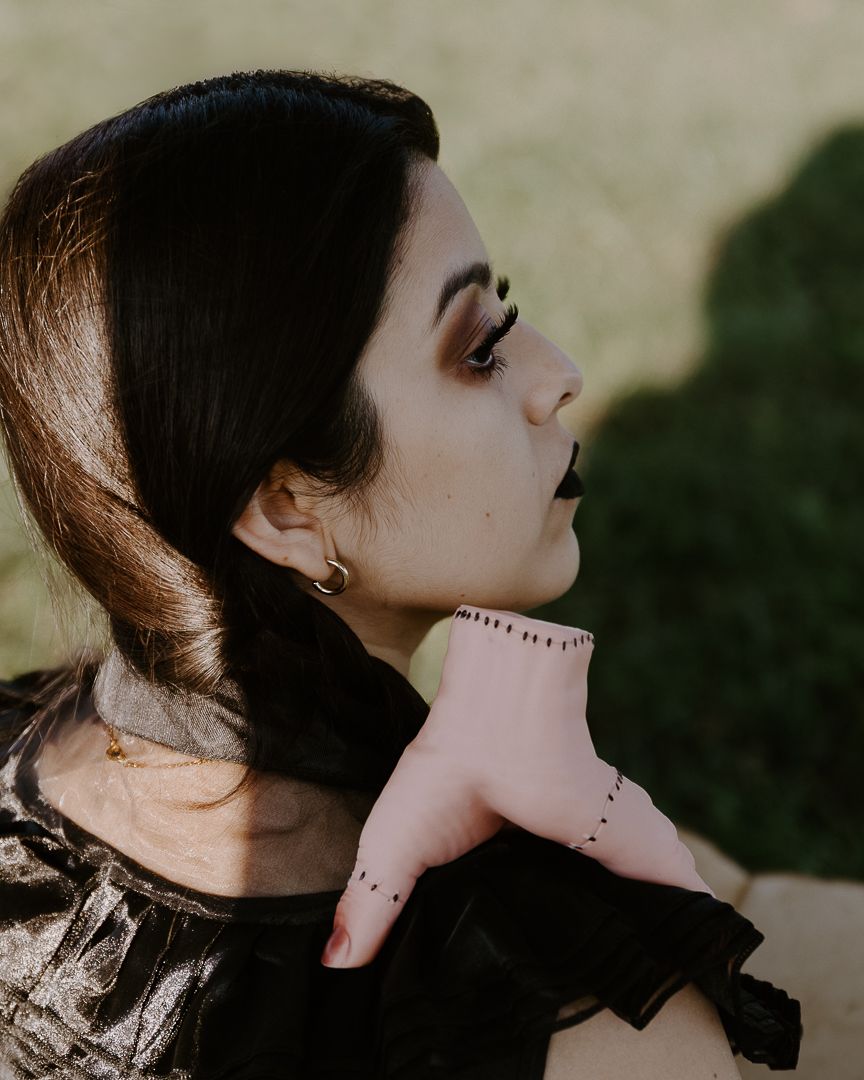 Dark artistic profile portrait with stitched makeup effect in moody lighting.