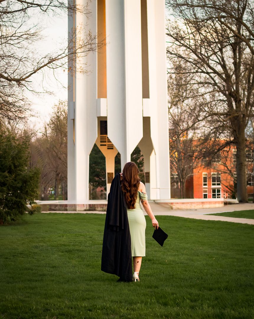 Graduates walk together around the grand white columns at sunset during their graduation ceremony.