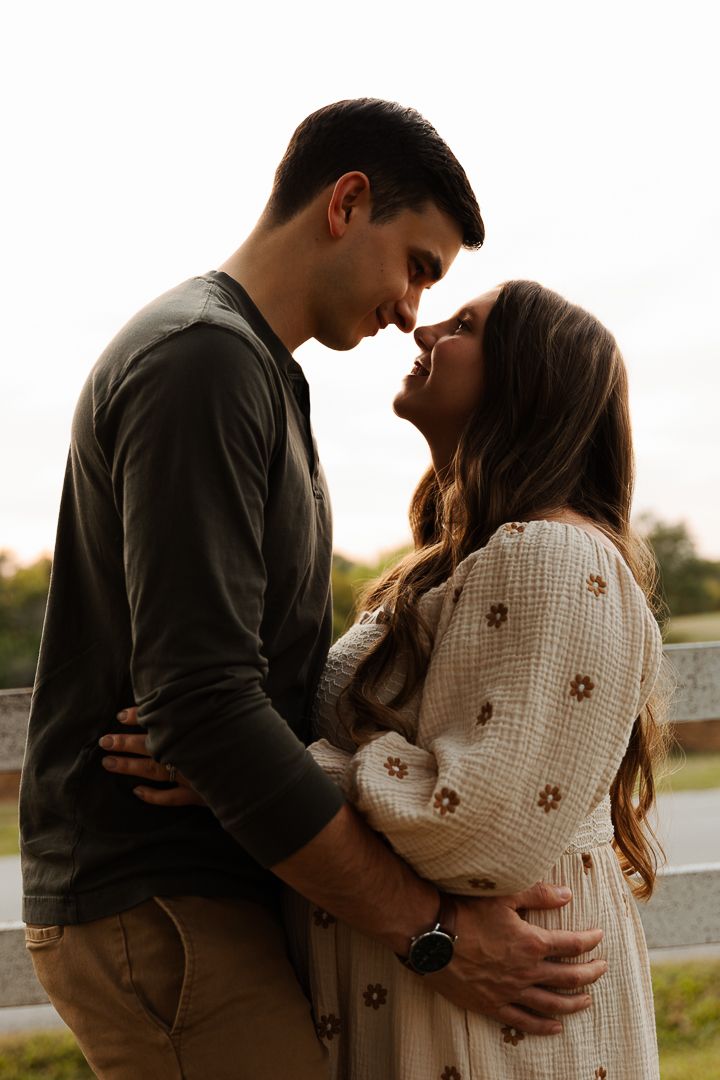 Silhouetted couple embracing against a bright white background in casual attire.