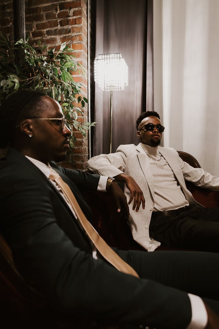 Two people relaxing on a leather couch in formal attire, captured in a candid conversation moment.