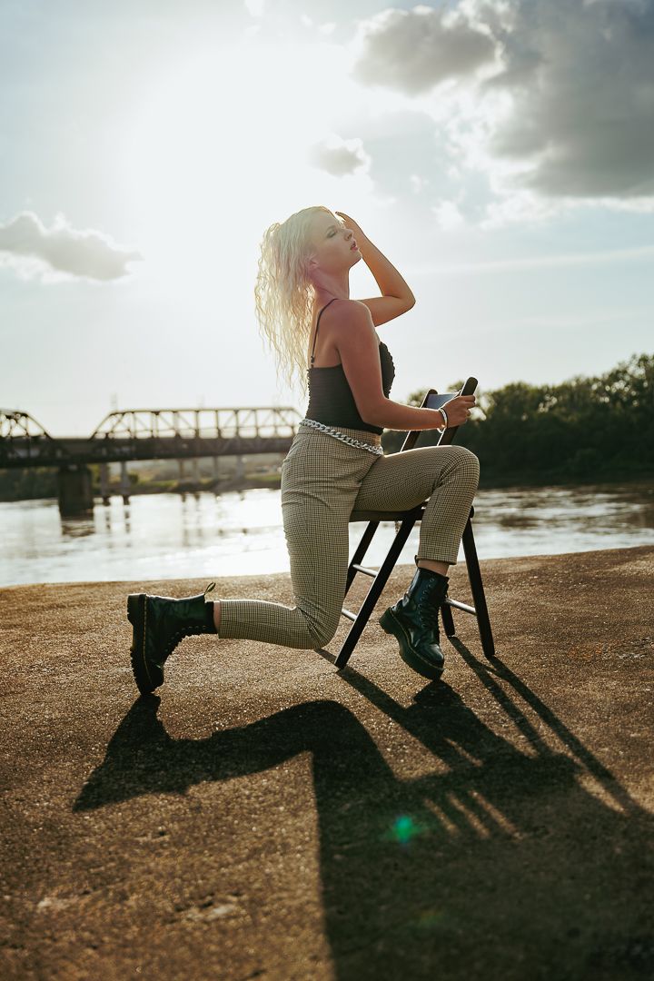 Dramatic sunset lighting illuminates yoga practice with chair prop against waterfront backdrop.