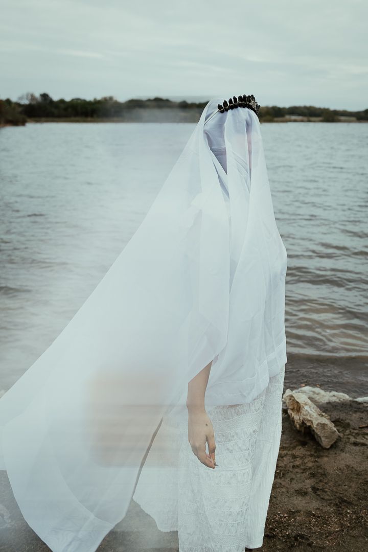 Ethereal white veil flowing in the wind against a moody lakeside landscape.