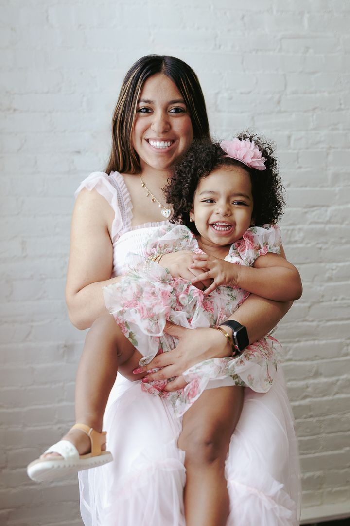 Series of portrait photos showing playful moments in matching pink and white outfits against a white brick wall.