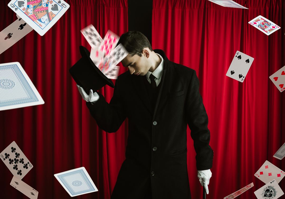 Playing cards scatter and float against a dramatic red curtain backdrop in a dynamic casino-themed composition.