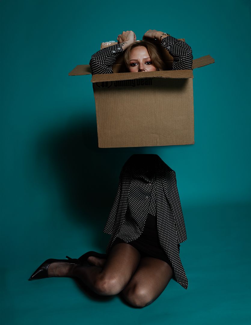 Artistic photo with cardboard box and polka dot dress against turquoise backdrop.