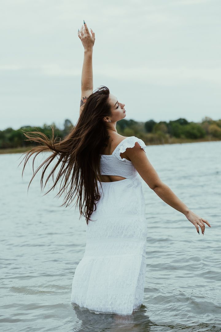 Artistic portrait series shows graceful movements in water while wearing an ethereal white dress at sunset.
