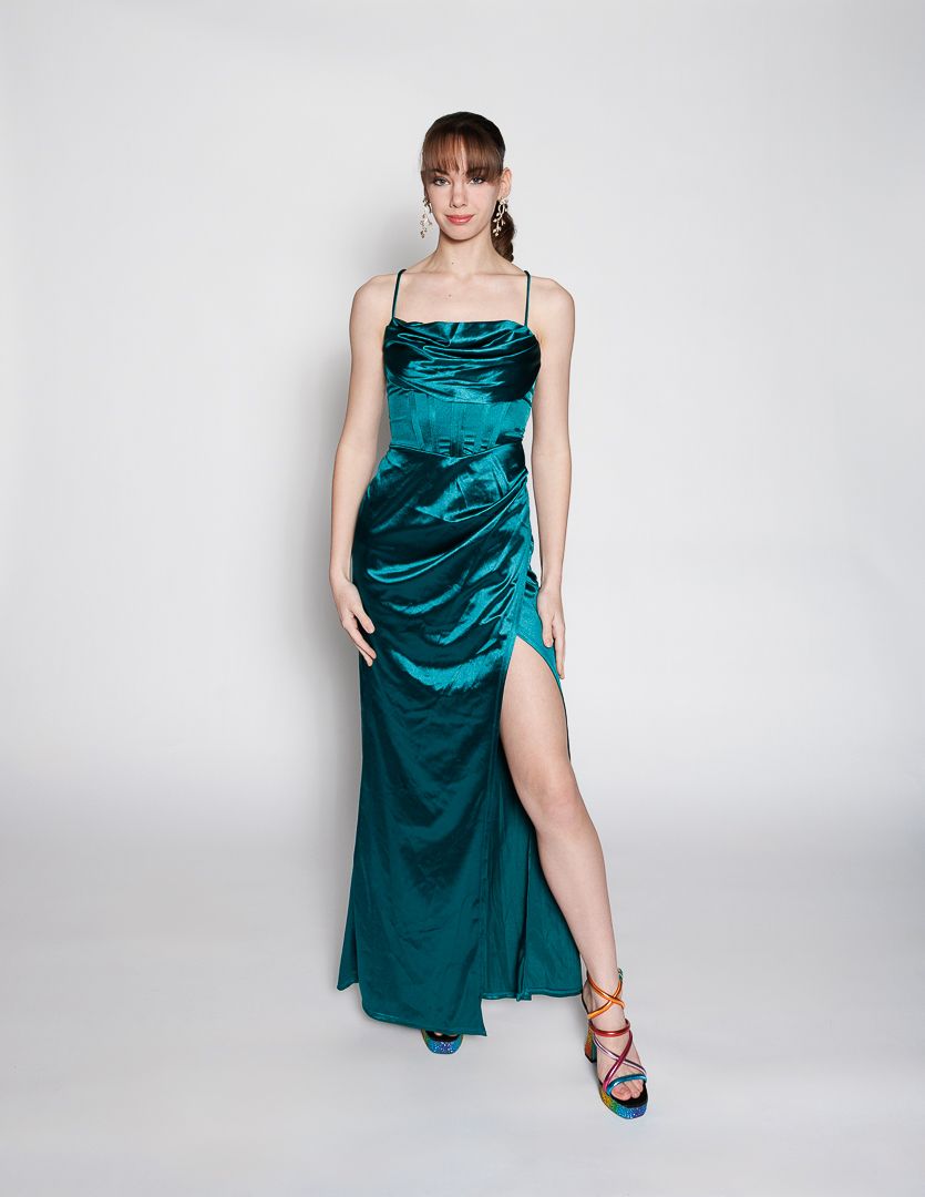 Woman wearing a teal satin maxi dress with spaghetti straps, ruched detail, and high slit, paired with colorful heels.