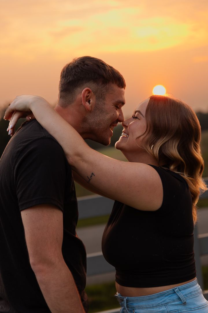 Romantic couple sharing a tender kiss at sunset with golden sky in the background.