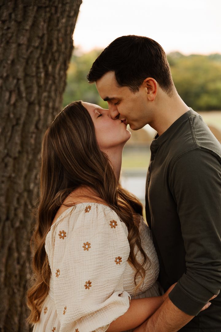 Maternity photo session featuring warm sunset lighting and tender moments between a couple near trees.