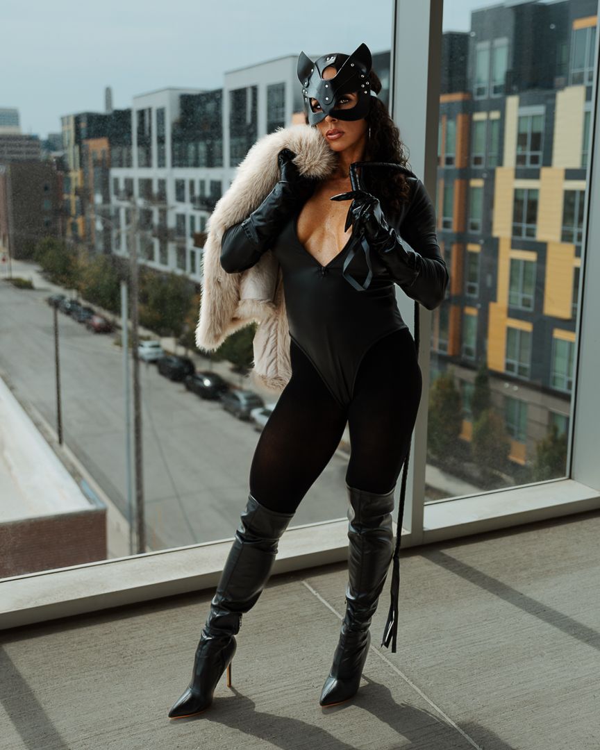 A silhouette poses dynamically against floor-to-ceiling windows with a city backdrop.