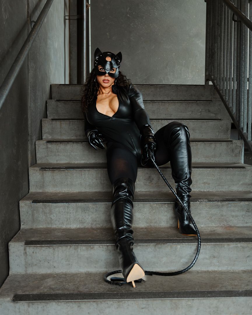 A fashion photoshoot on grey stone steps featuring leather boots and dramatic poses in black attire.