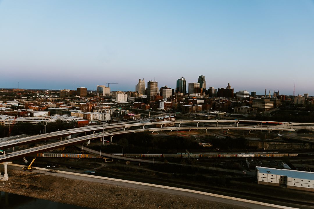 Panoramic aerial view of Kansas City skyline with sweeping highways and urban landscape at dusk.