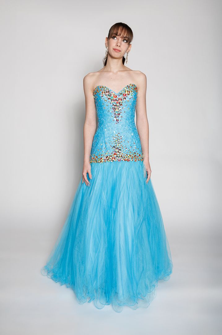Woman wearing a strapless blue tulle ball gown with colorful crystal embellishments on the fitted bodice.