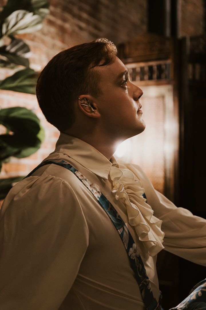 Dramatic side profile portrait in vintage-style clothing with warm lighting.