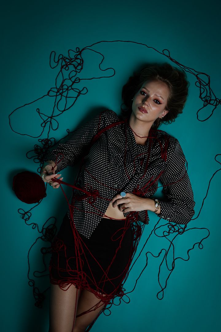 Artistic fashion photo with overlaid black scribble designs against dark teal backdrop.