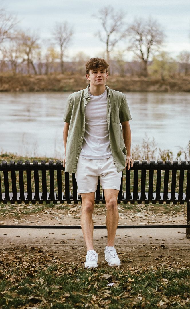 A sequence of photos showing someone sitting on a park bench near a river on an autumn day wearing white shorts and olive jacket.