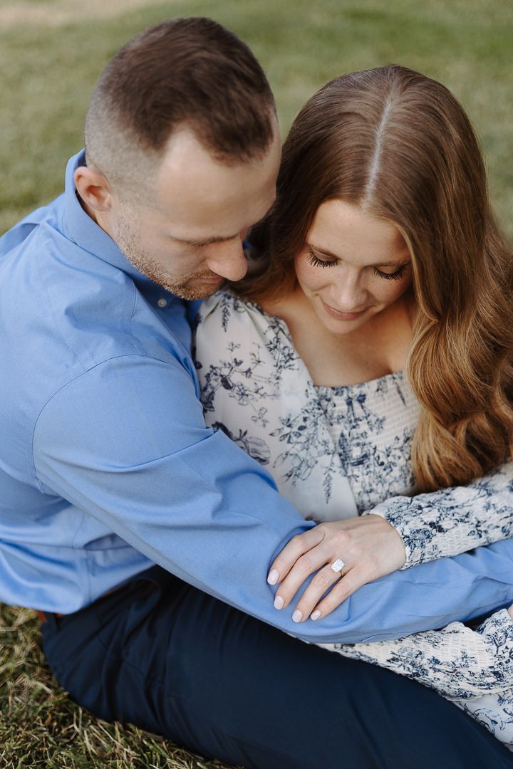 Intimate couple poses lying in grass during engagement photography session.