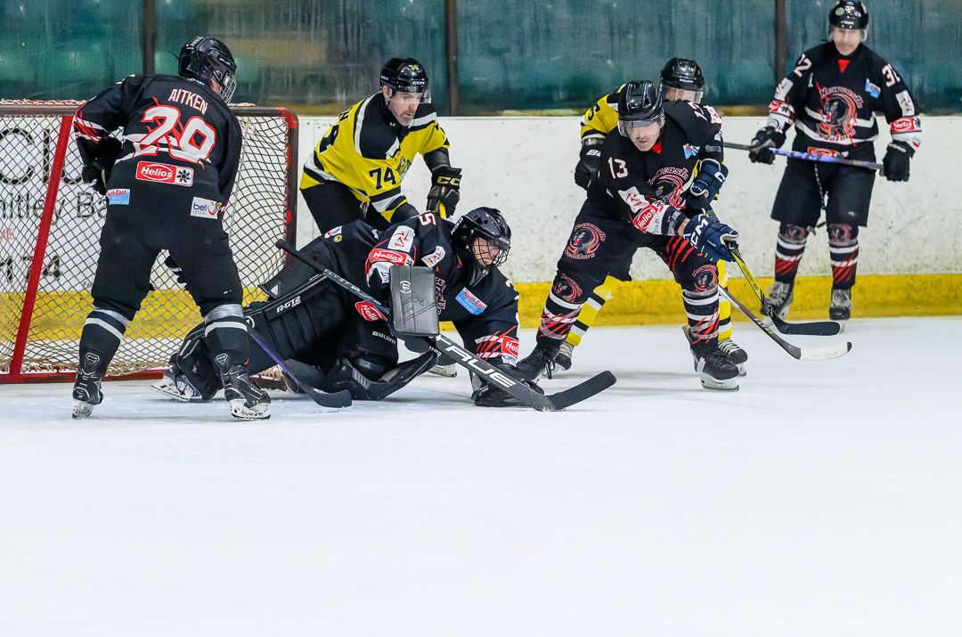 Ice hockey players battle for the puck during the opening face-off of a competitive ice hockey match.