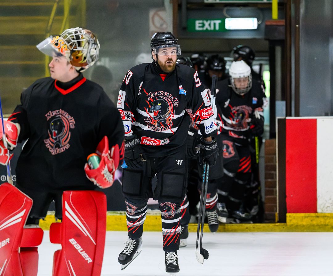 Ice hockey players skate onto the ice before a competitive match, ready for the opening face-off.