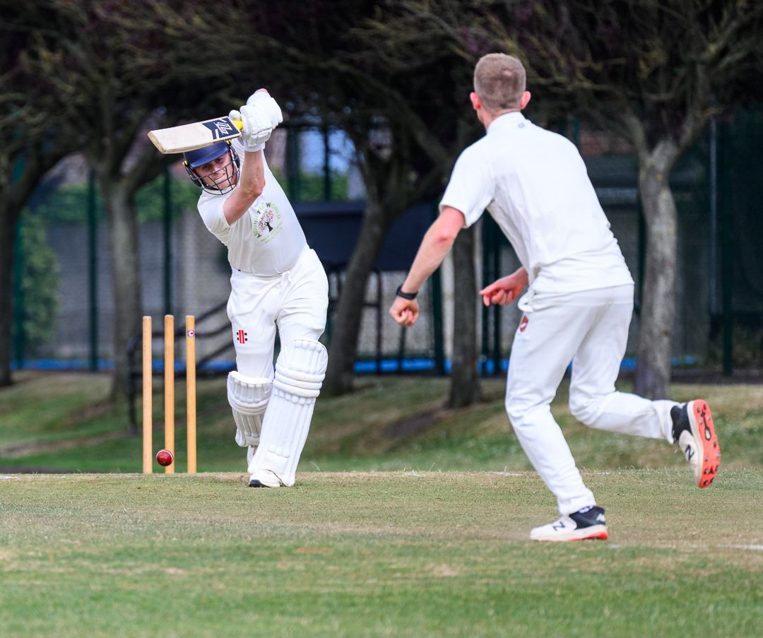 Cricket bowler delivers the ball during a competitive grassroots cricket match