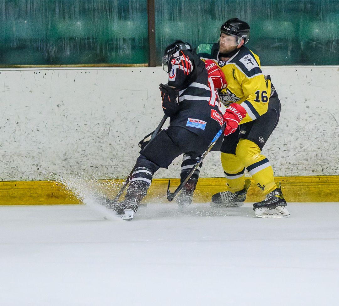 Ice hockey players battle for the puck during the opening face-off of a competitive ice hockey match.