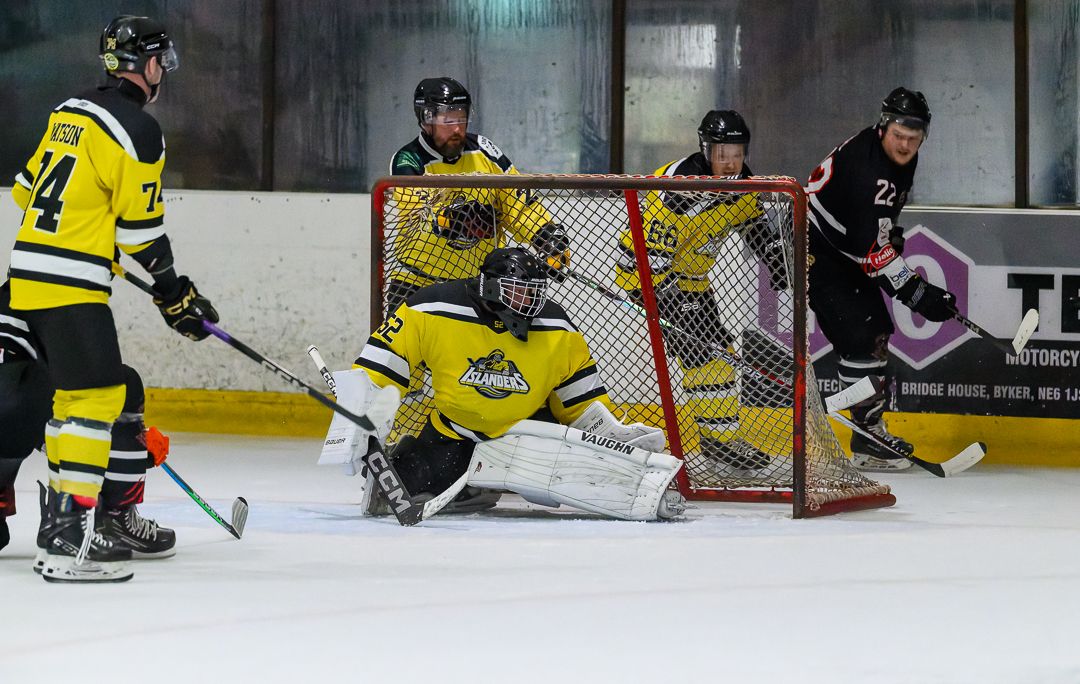 Ice hockey goalkeeper makes a crucial save as attackers battle for the puck during an intense match.