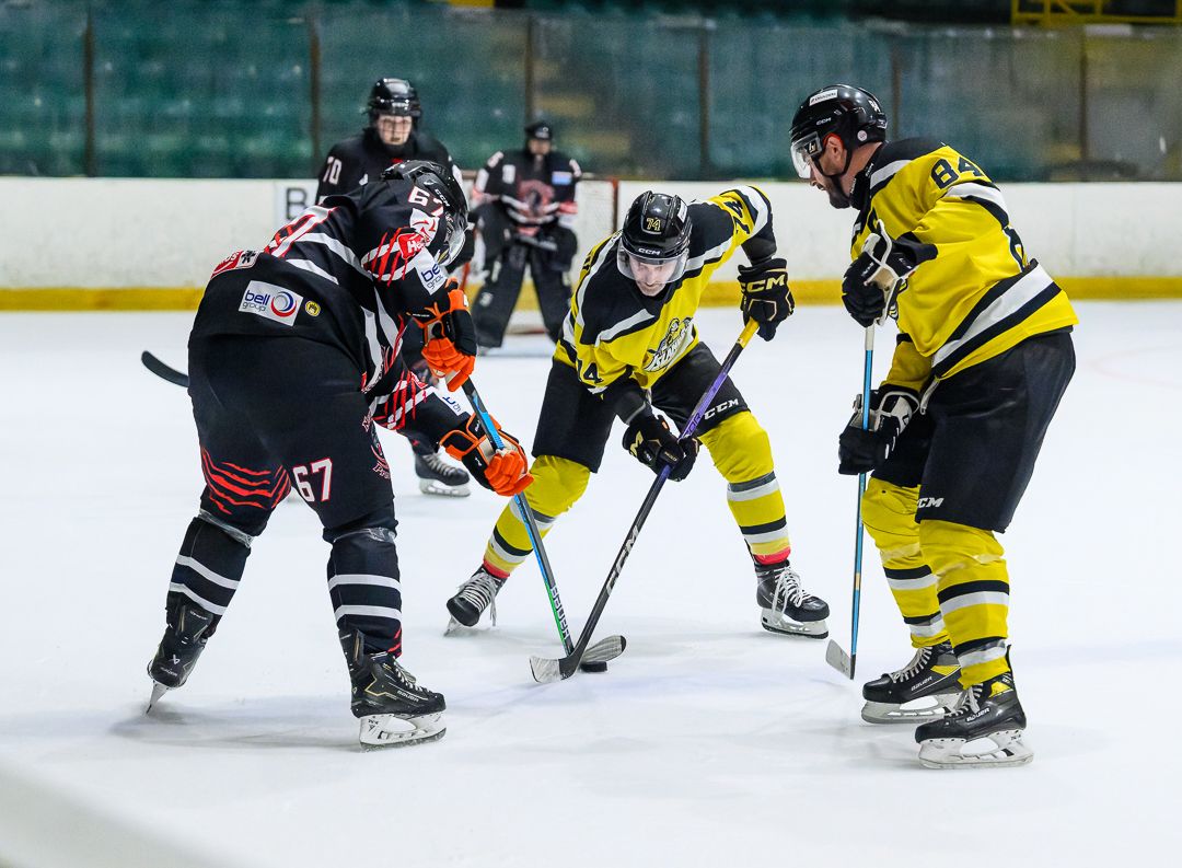 Ice hockey players battle for the puck during the opening face-off of a competitive ice hockey match.