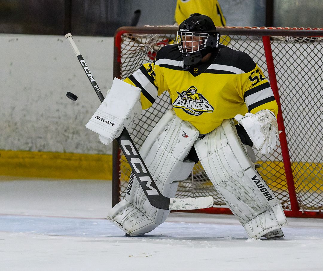 Ice hockey goalkeeper stands ready in front of the net during a competitive ice hockey match.