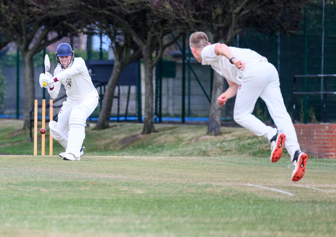 Cricket bowler delivers the ball during a competitive grassroots cricket match