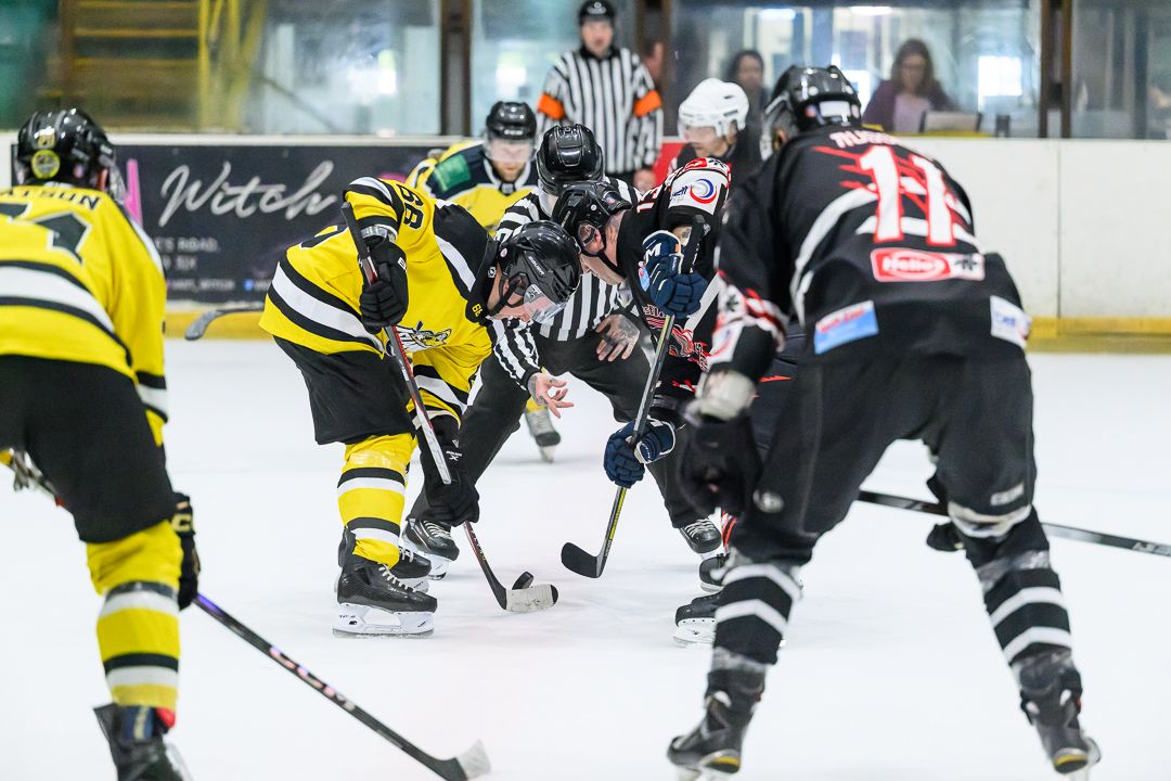 Ice hockey face-off as players battle for puck possession during a fast-paced competitive match.