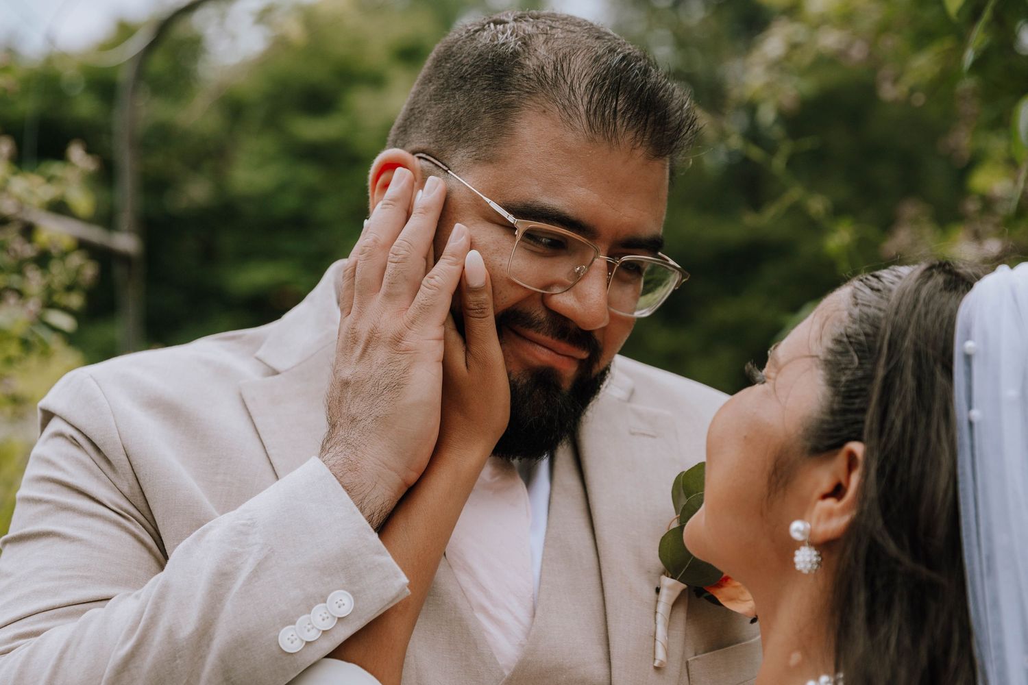 Groom looks lovingly into his new bride’s eyes while holding her hand to his face