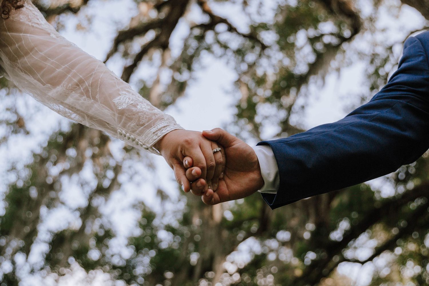 Bride and Groom hold hands in a way that shows off the Brides engagement ring and wedding band
