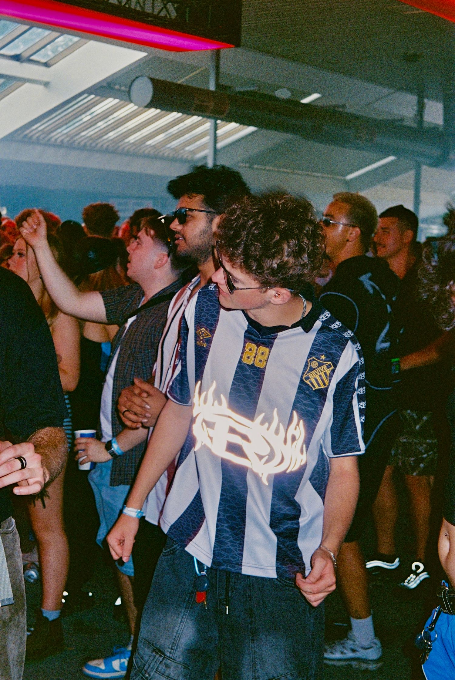 Group of young men in streetwear dancing at indoor music event.