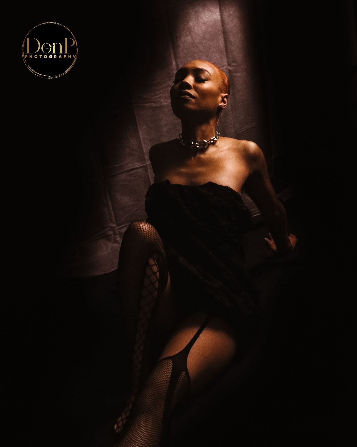 Dramatic boudoir photography portrait with focused lighting, highlighting posture, texture, and cinematic depth.