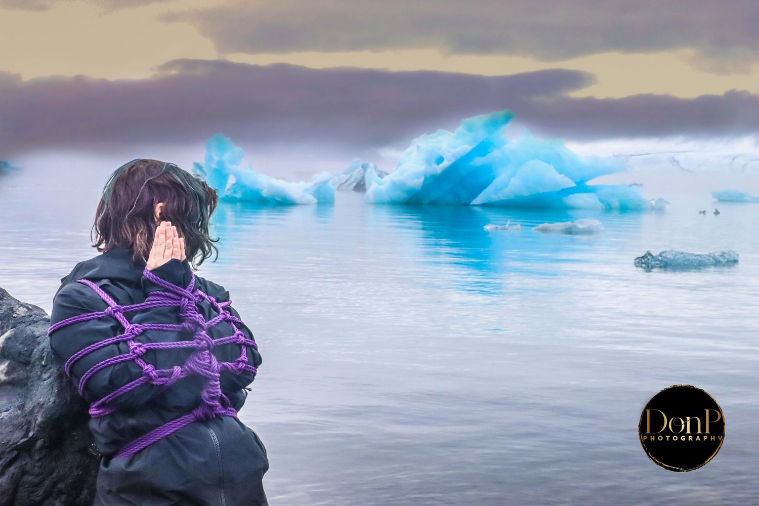Outdoor portrait of a person bound in purple rope near icy water, blending shibari-inspired rope art with natural landscape photography.