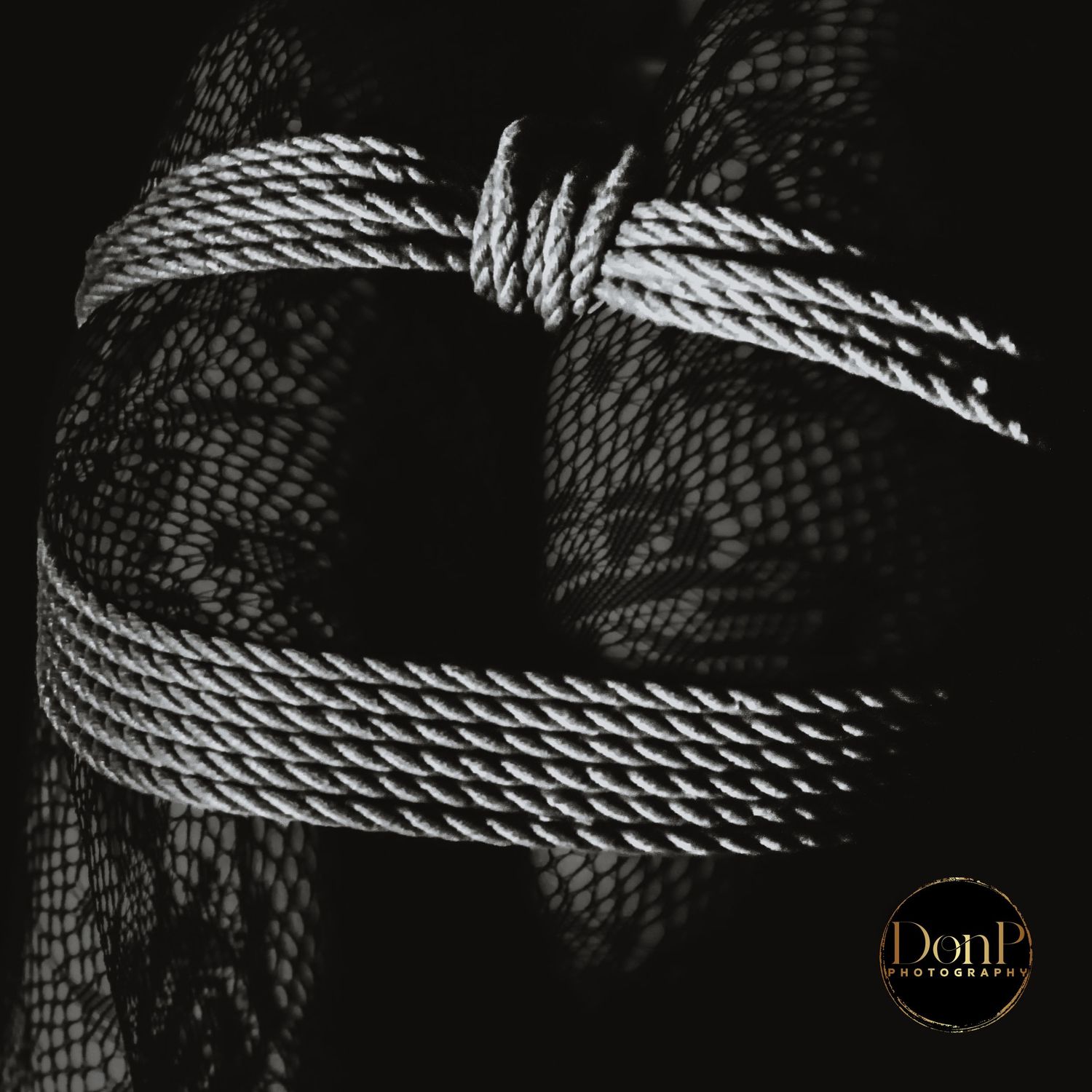 Black-and-white conceptual detail of rope texture and fabric, focusing on form, contrast, and symbolic restraint.