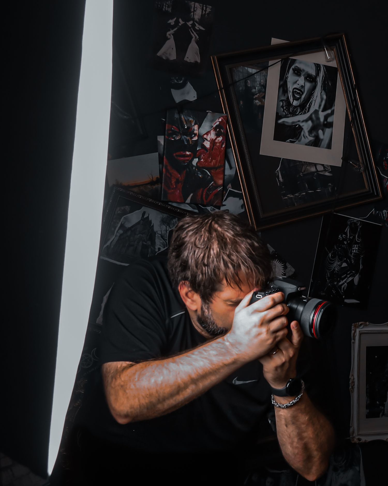 Photographer capturing a moody portrait in a dark studio surrounded by edgy, gothic artwork. boudoir