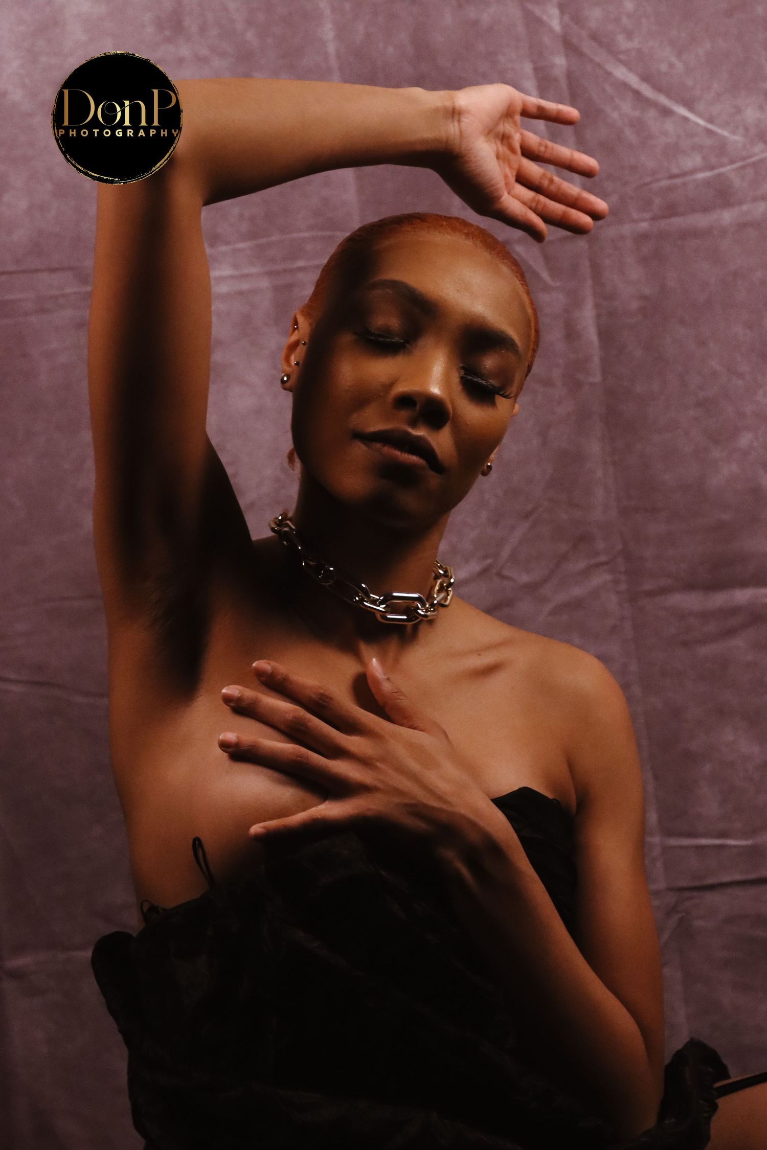 Artistic boudoir photography portrait using raised posture and directional light to convey grace and emotional openness.