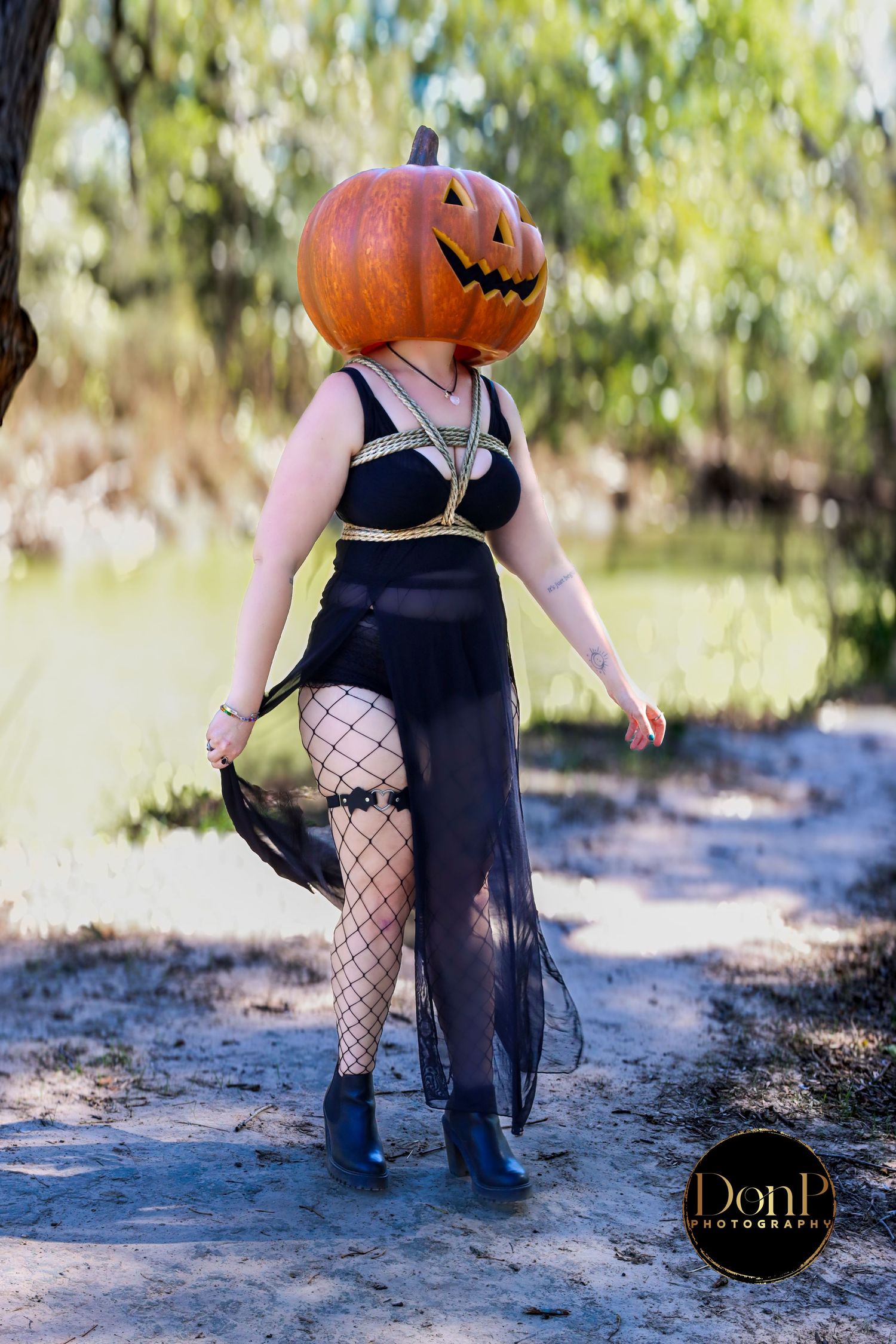 Seasonal Halloween portrait with pumpkin mask and flowing black dress, blending fantasy, confidence, and playful outdoor storytelling.